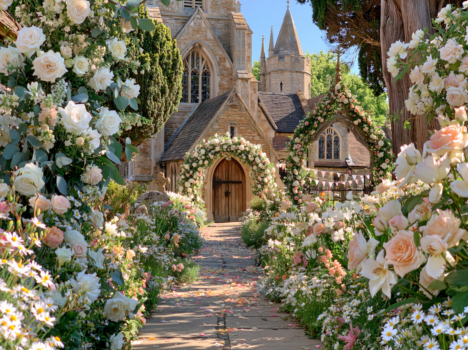 A flower-lined garden path leading to a country church with a rose-covered porch